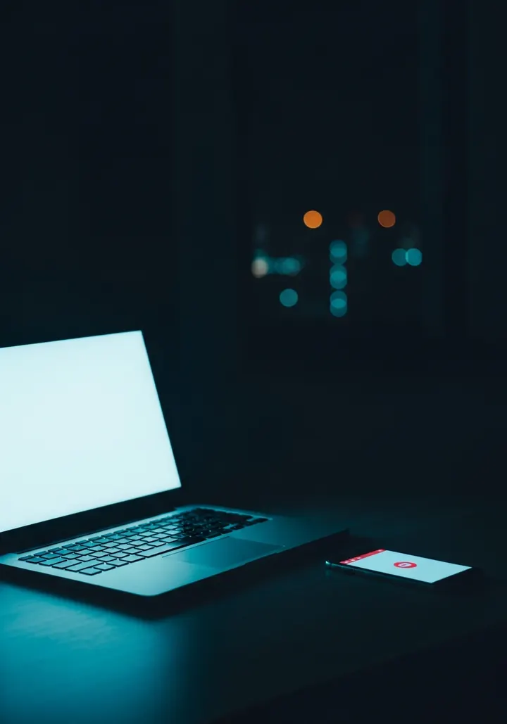 Glowing laptop in a dark room with a dark web alert