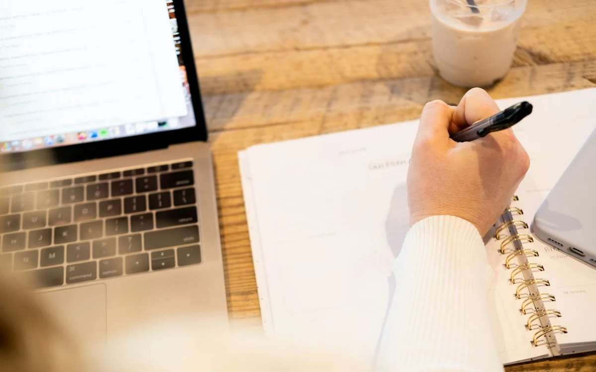 File photograph of a person making notes beside a laptop, illustrating the work involved in manual privacy requests.