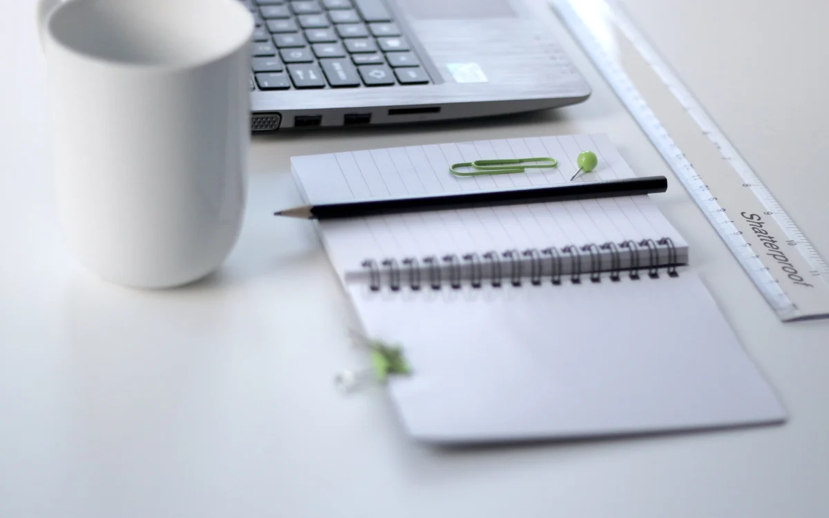 Illustrative photograph of a laptop, notebook and pen for organising identity-theft recovery steps.