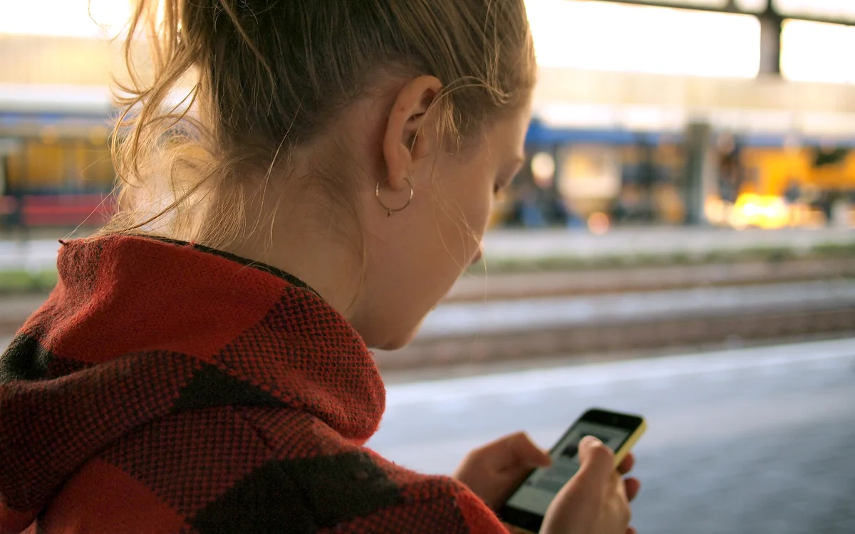 Illustrative photograph of a woman checking her smartphone. Not a depicted identity-theft victim.